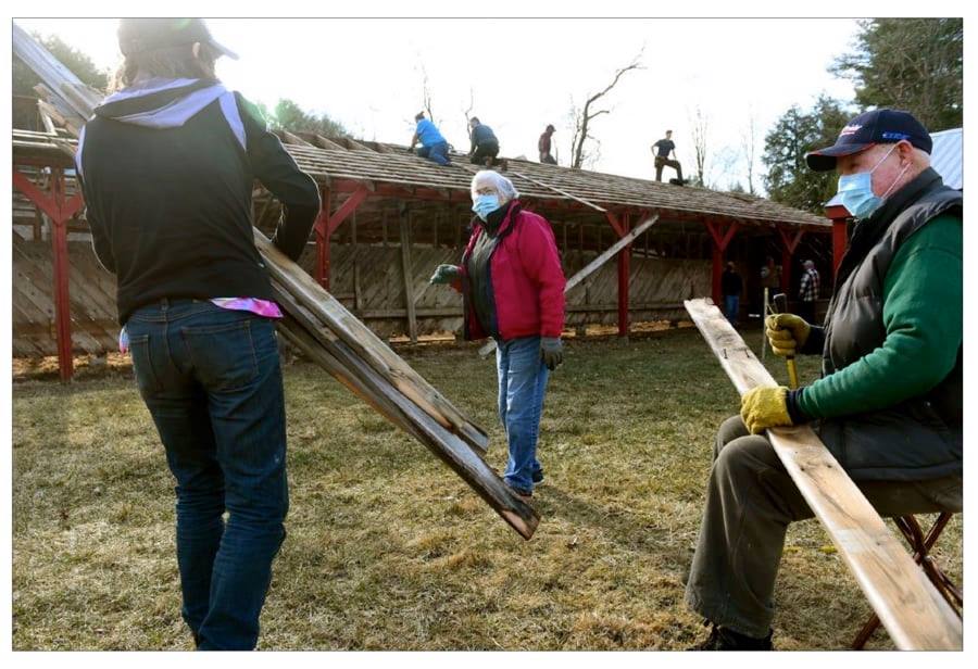 A group of people wearing masks are working on a roof