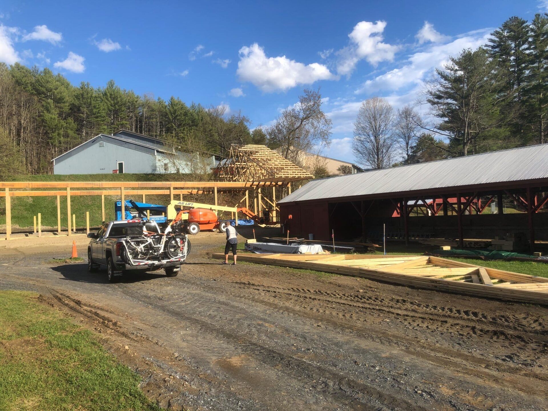 A truck is parked on the side of a dirt road in front of a building under construction.