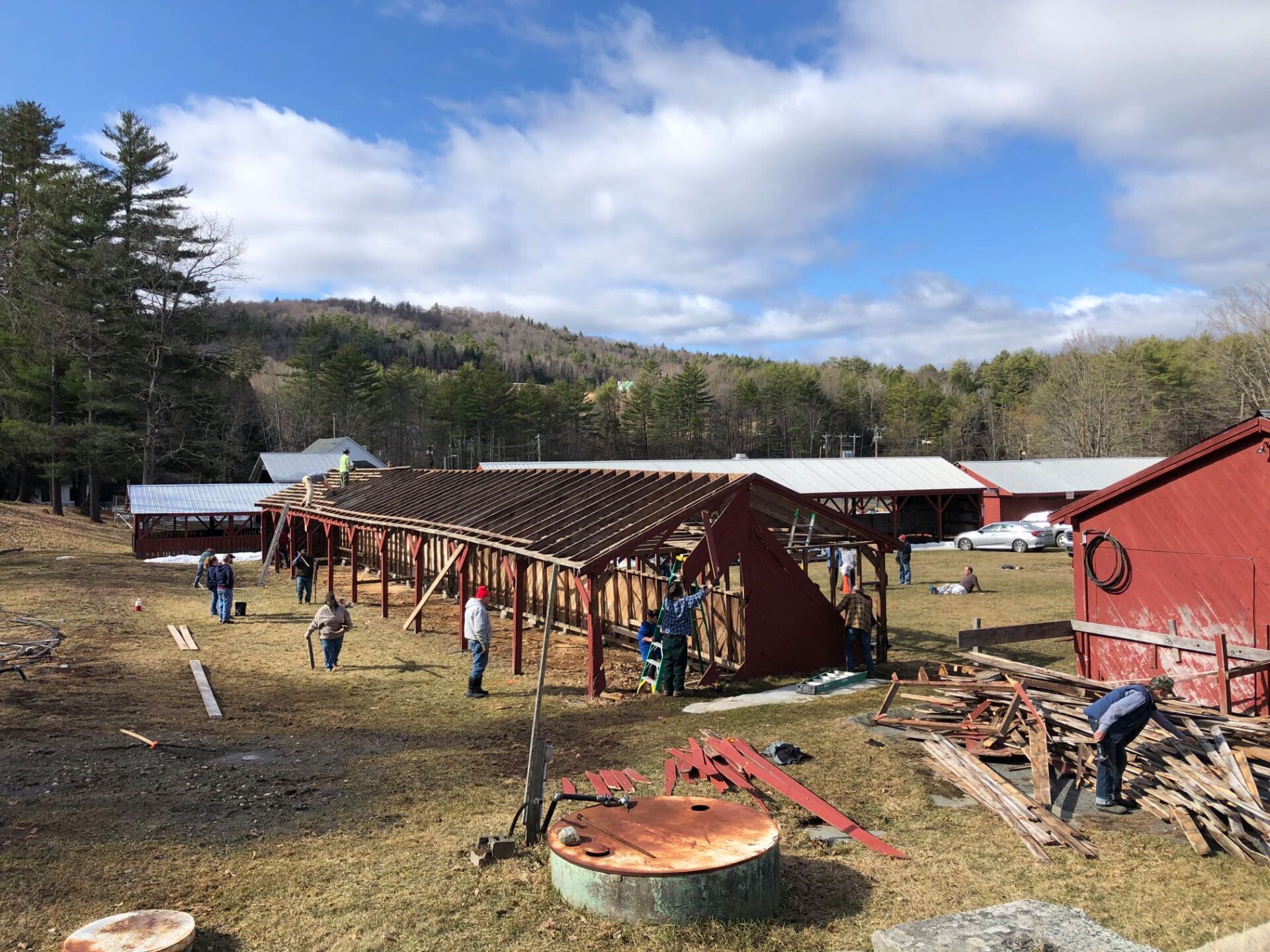 A group of people are working on a barn in a field.