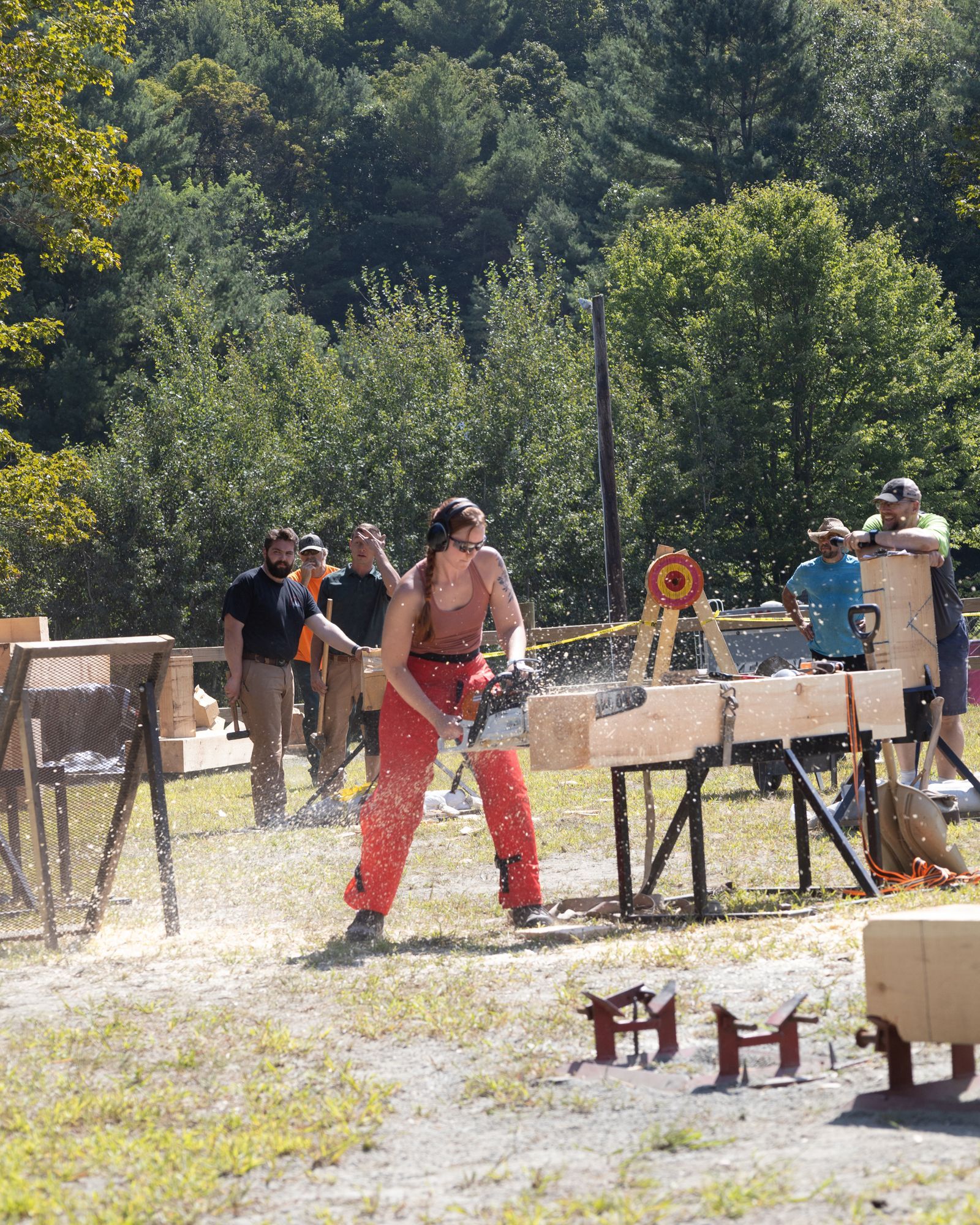 Outdoor archery range with people aiming at targets among trees and wooden stands
