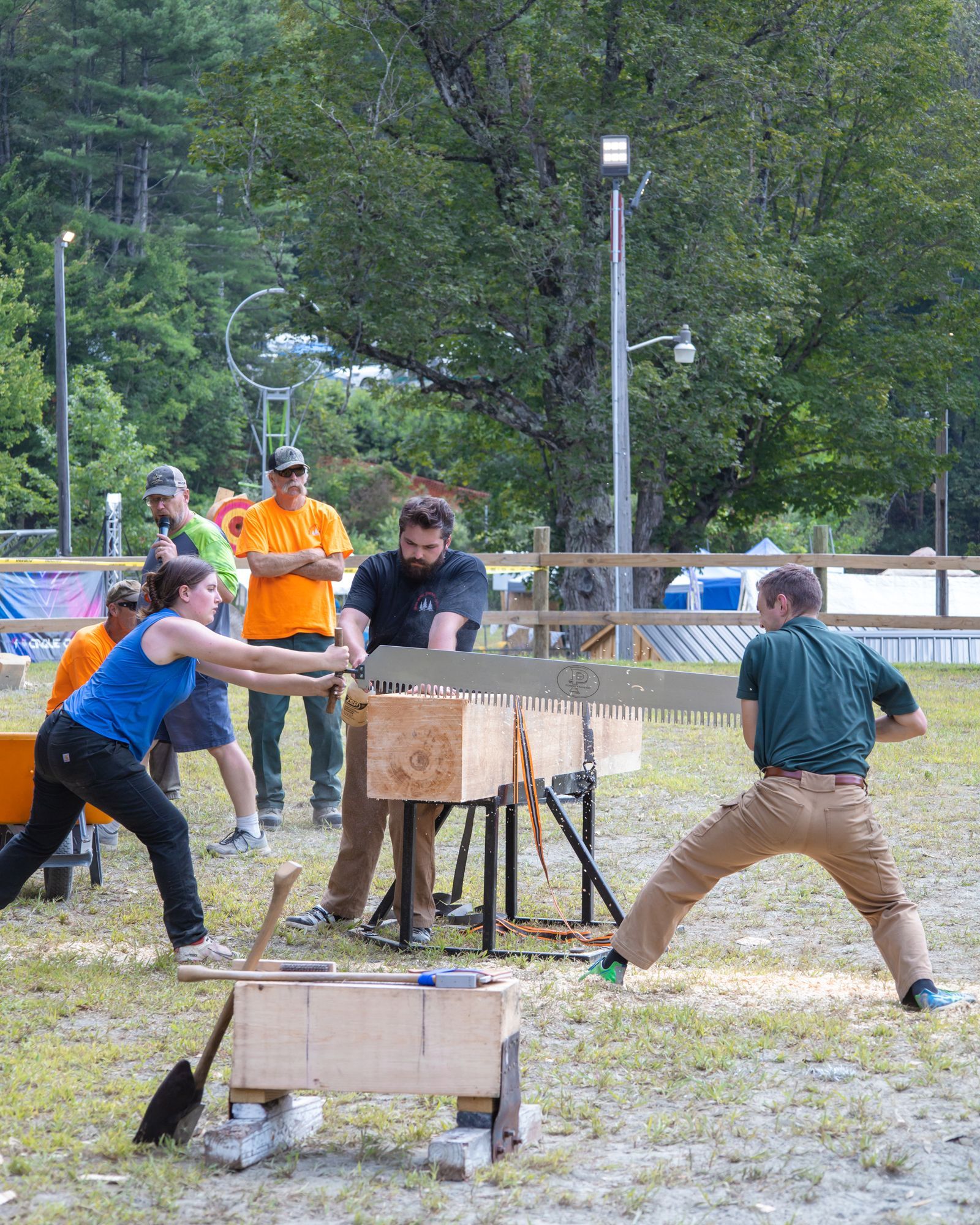 People pulling on a wooden cart in an outdoor grassy field during a competition