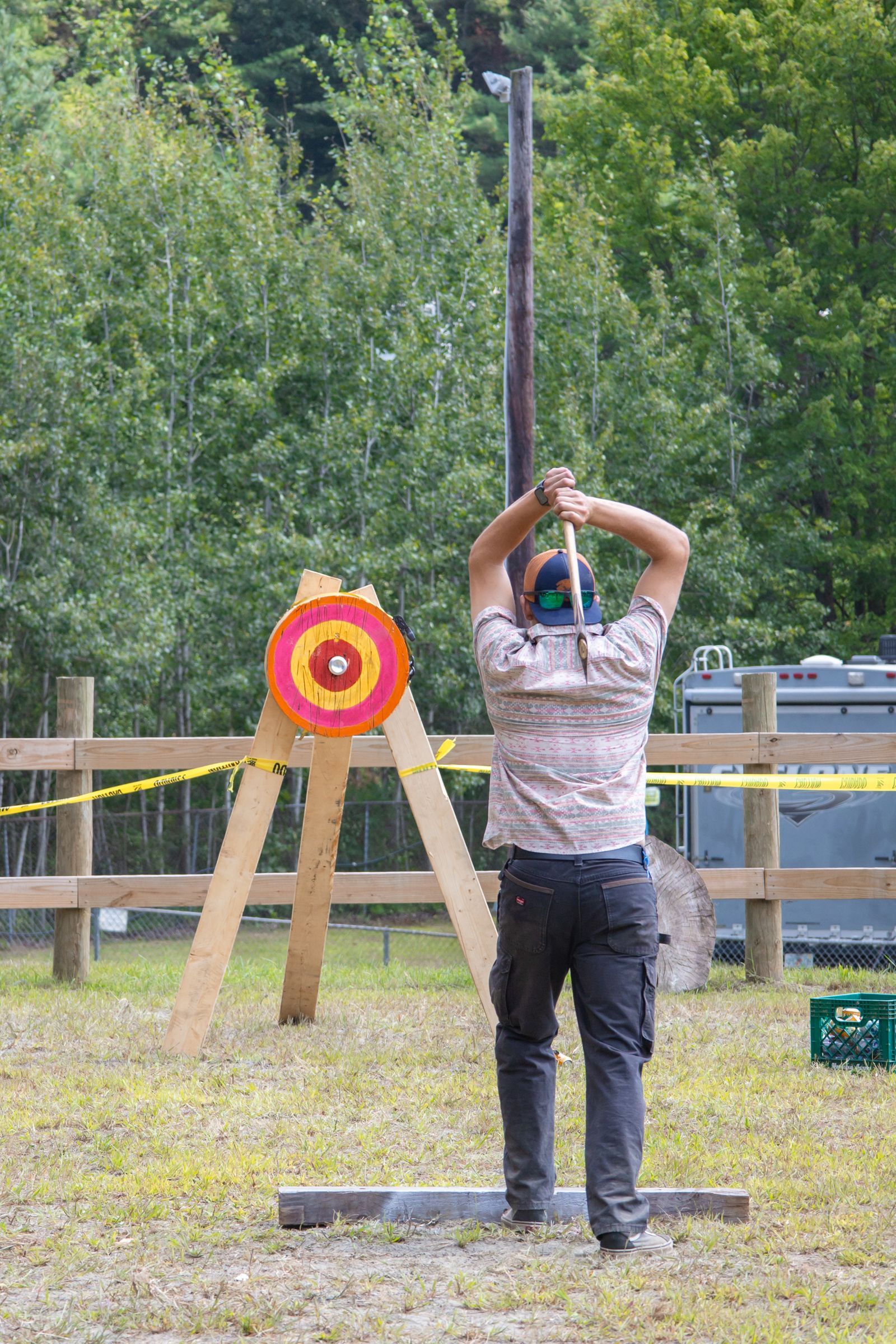 Person aiming at a target with an axe in an outdoor archery range.