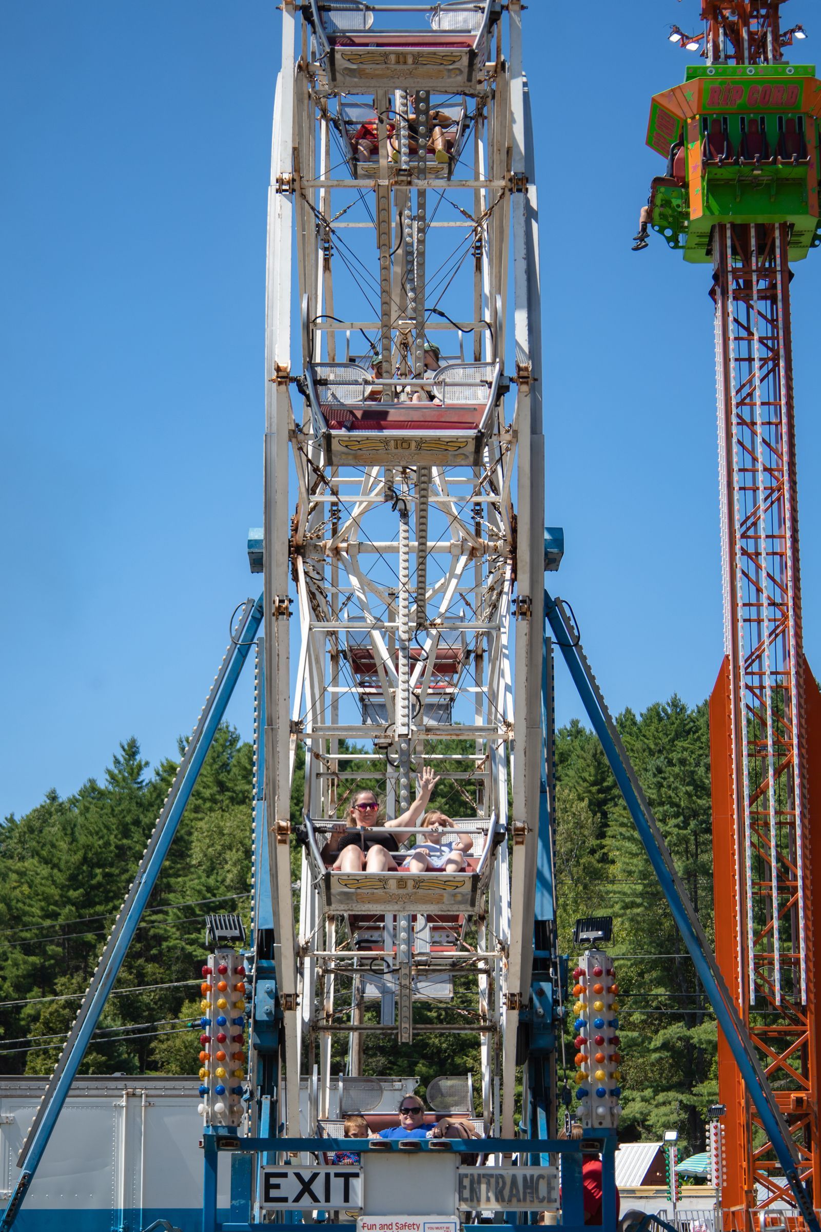 Ferris wheel with riders at an amusement park under a clear blue sky