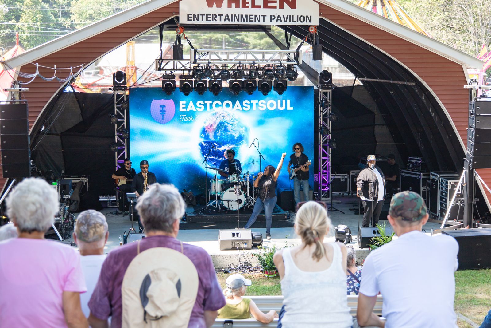 Outdoor concert stage with East Coast Soul performing before a seated audience