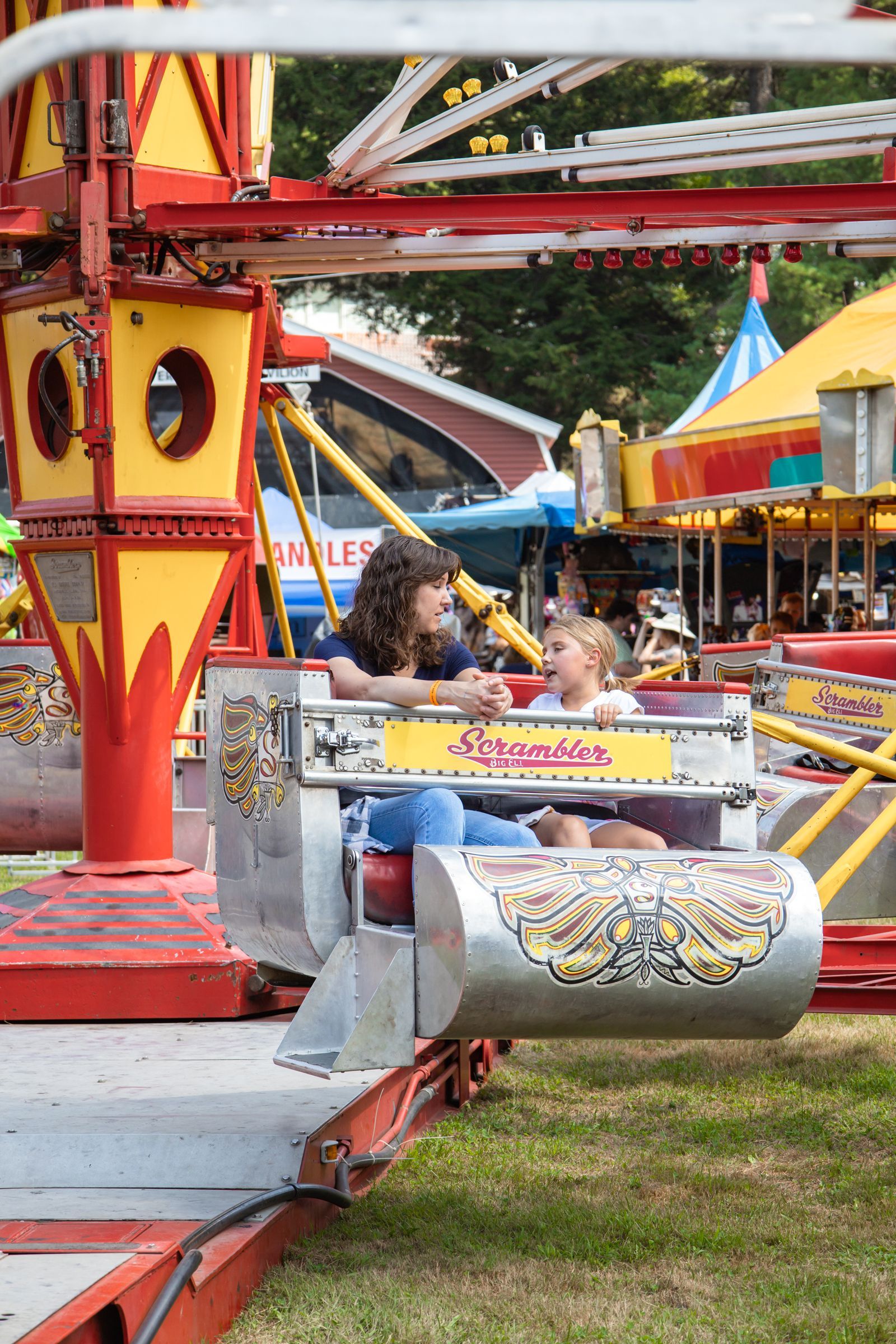 Child riding a small carnival ride with red and yellow cars in an amusement park