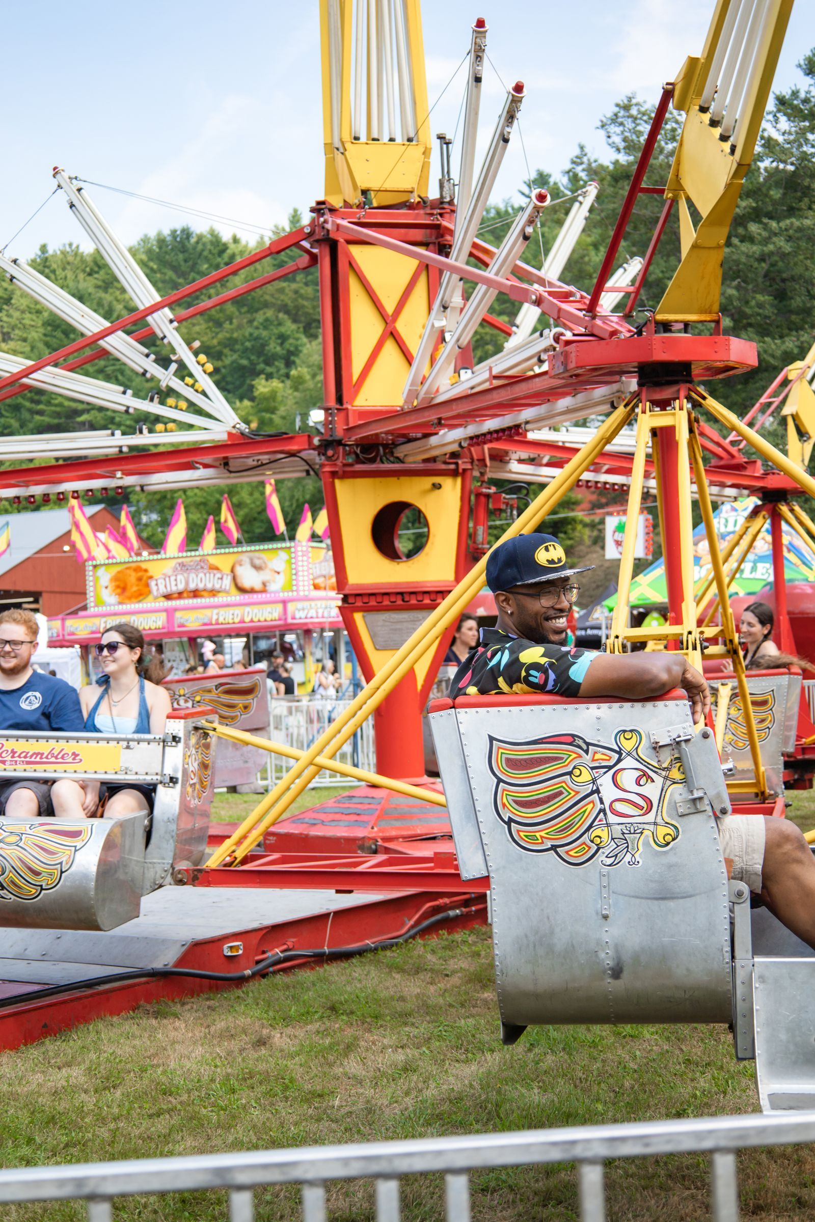 Colorful amusement ride with people seated in metal cars at an outdoor fairground