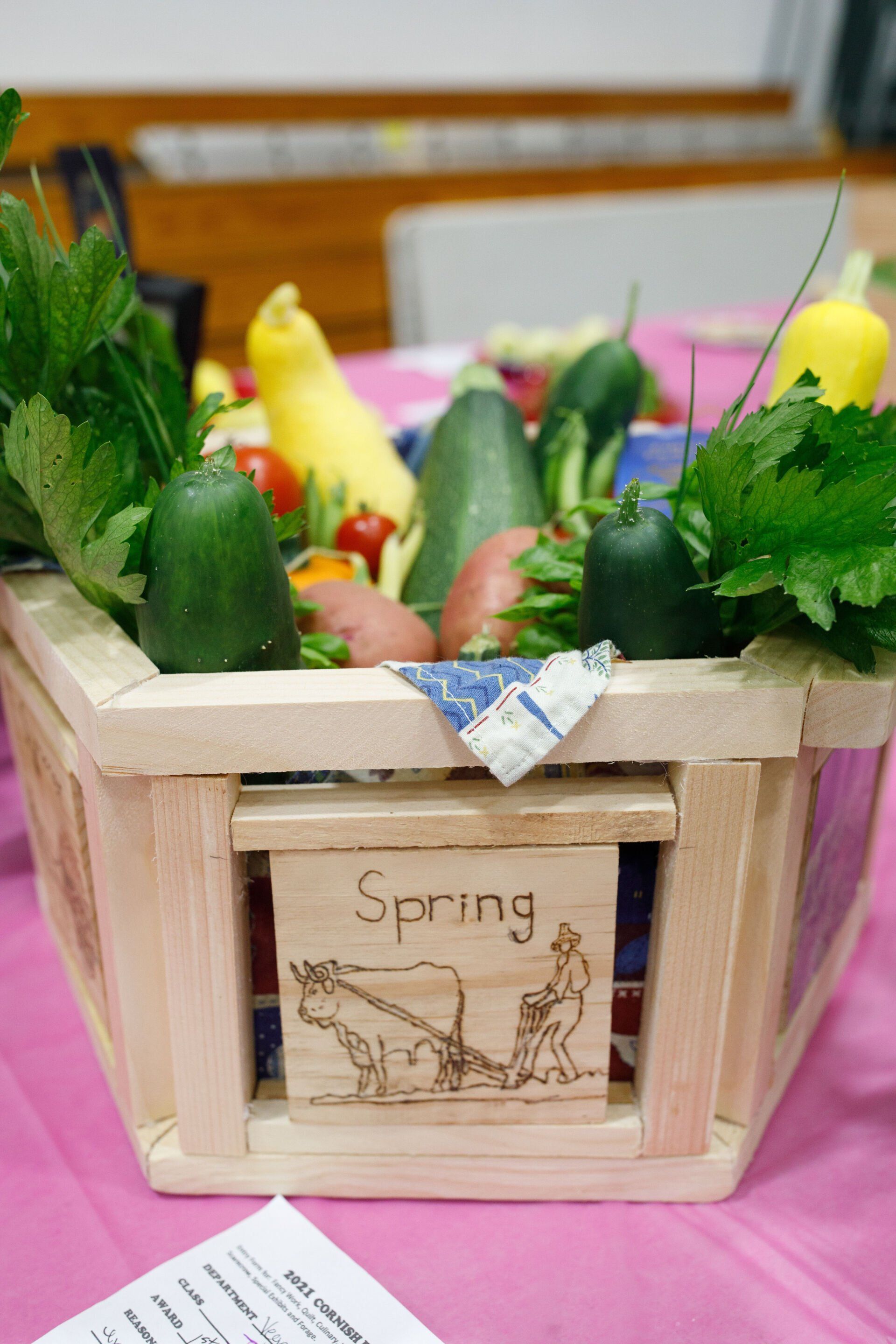A wooden box filled with vegetables and a sign that says spring