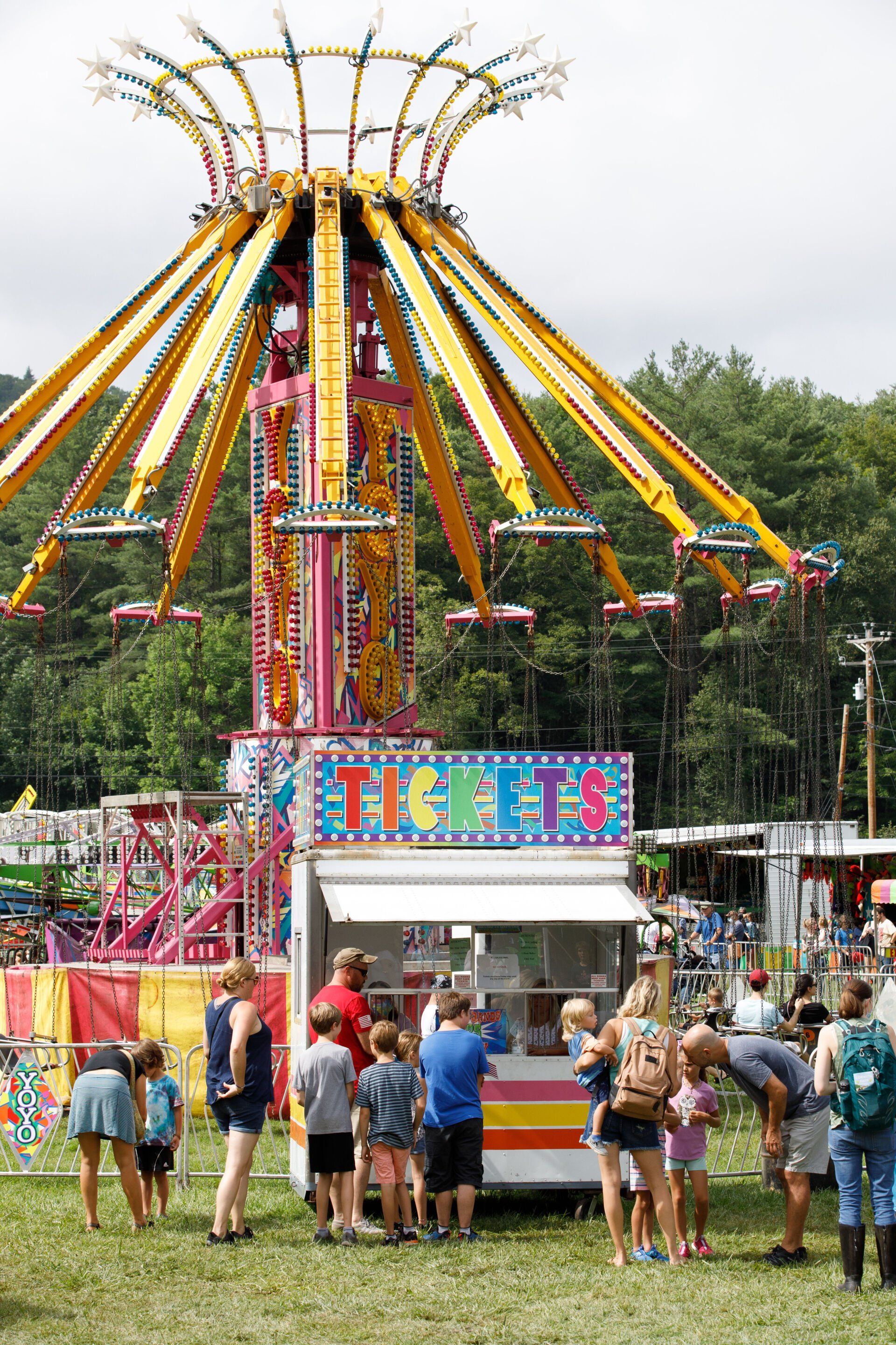 A group of people are standing in front of a carnival ride.