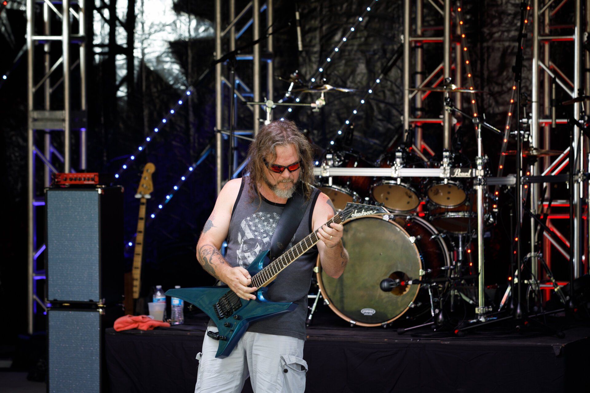 A man is playing a guitar on stage in front of a drum set
