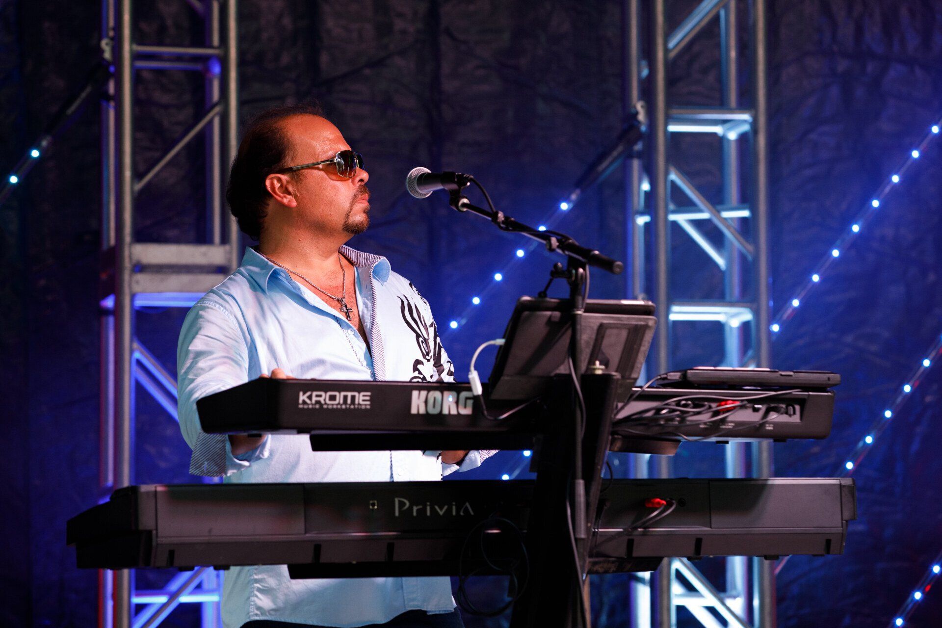 A man is playing a korg keyboard and singing into a microphone