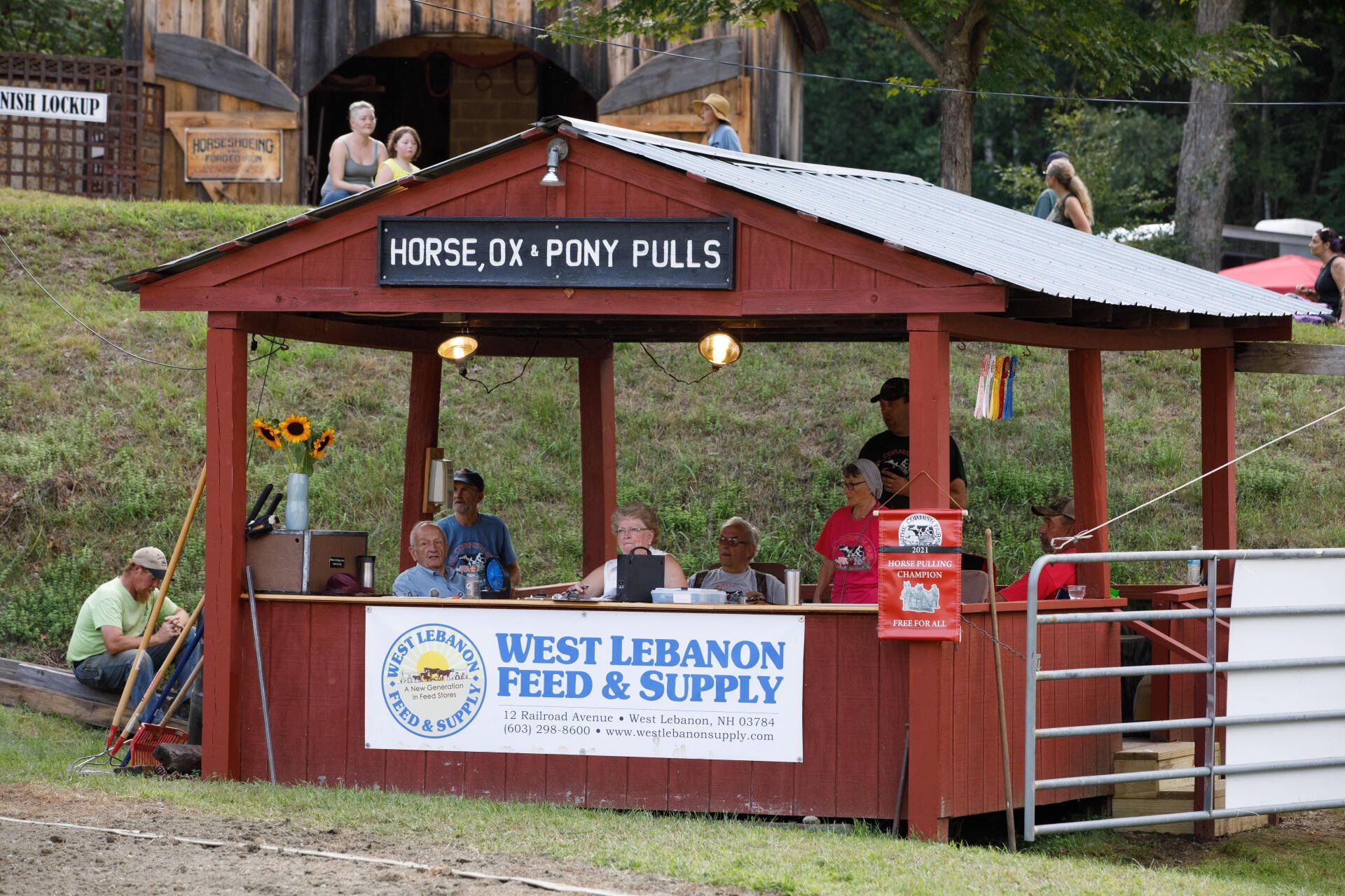 A group of people are standing in front of a shed that says west lebanon feed & supply