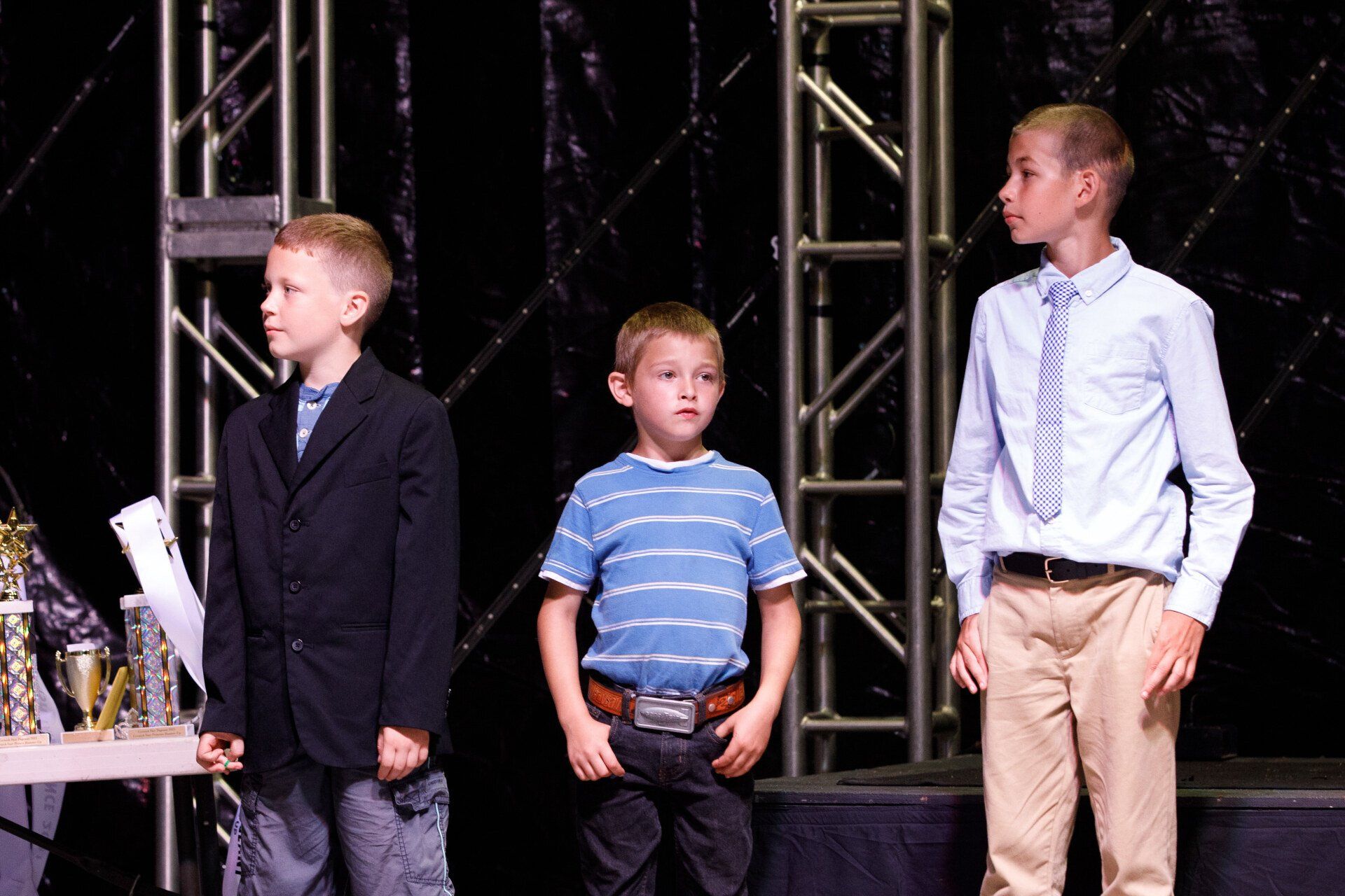 Three young boys are standing next to each other on a stage.