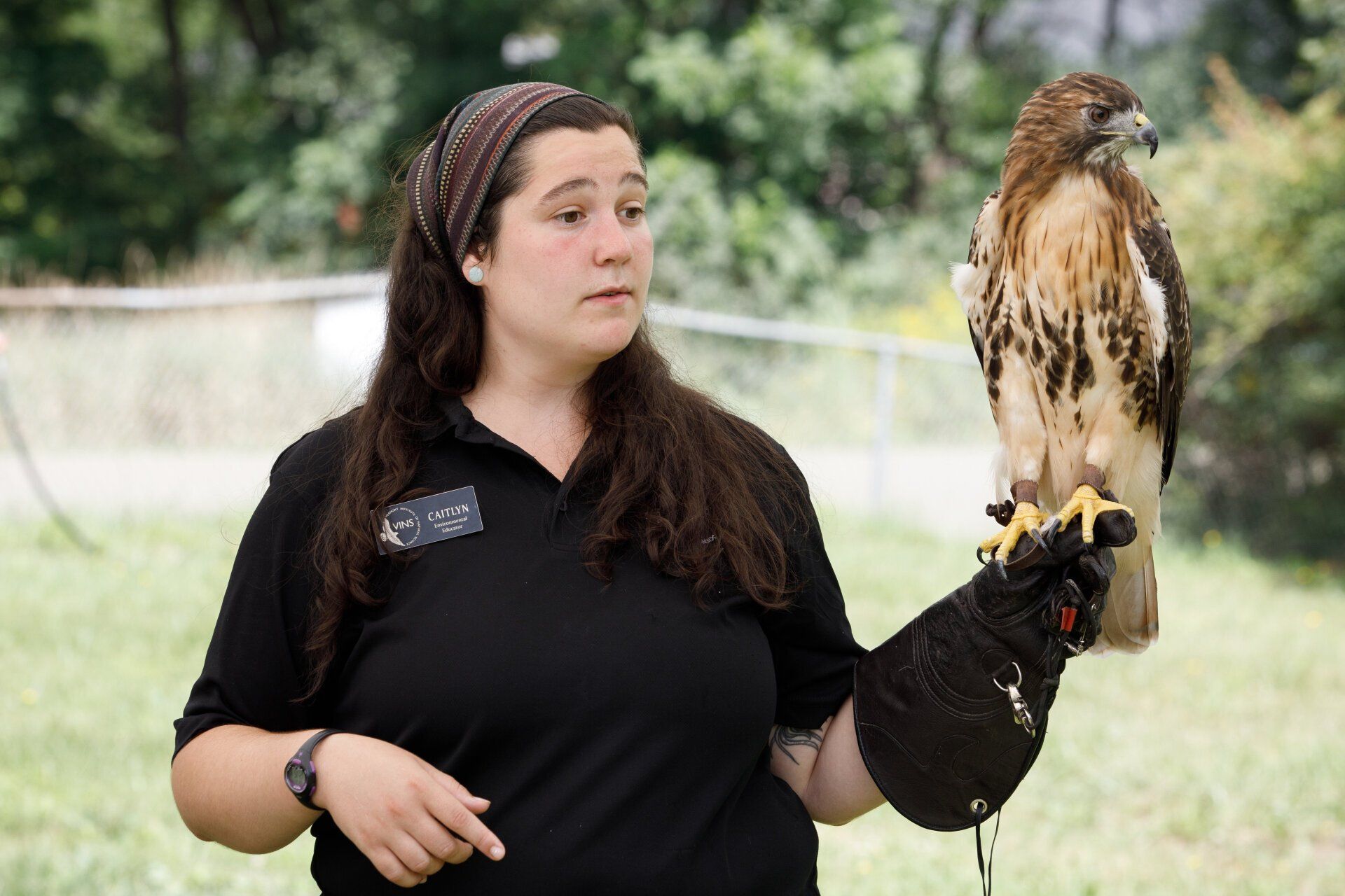 A woman is holding a bird on her arm.