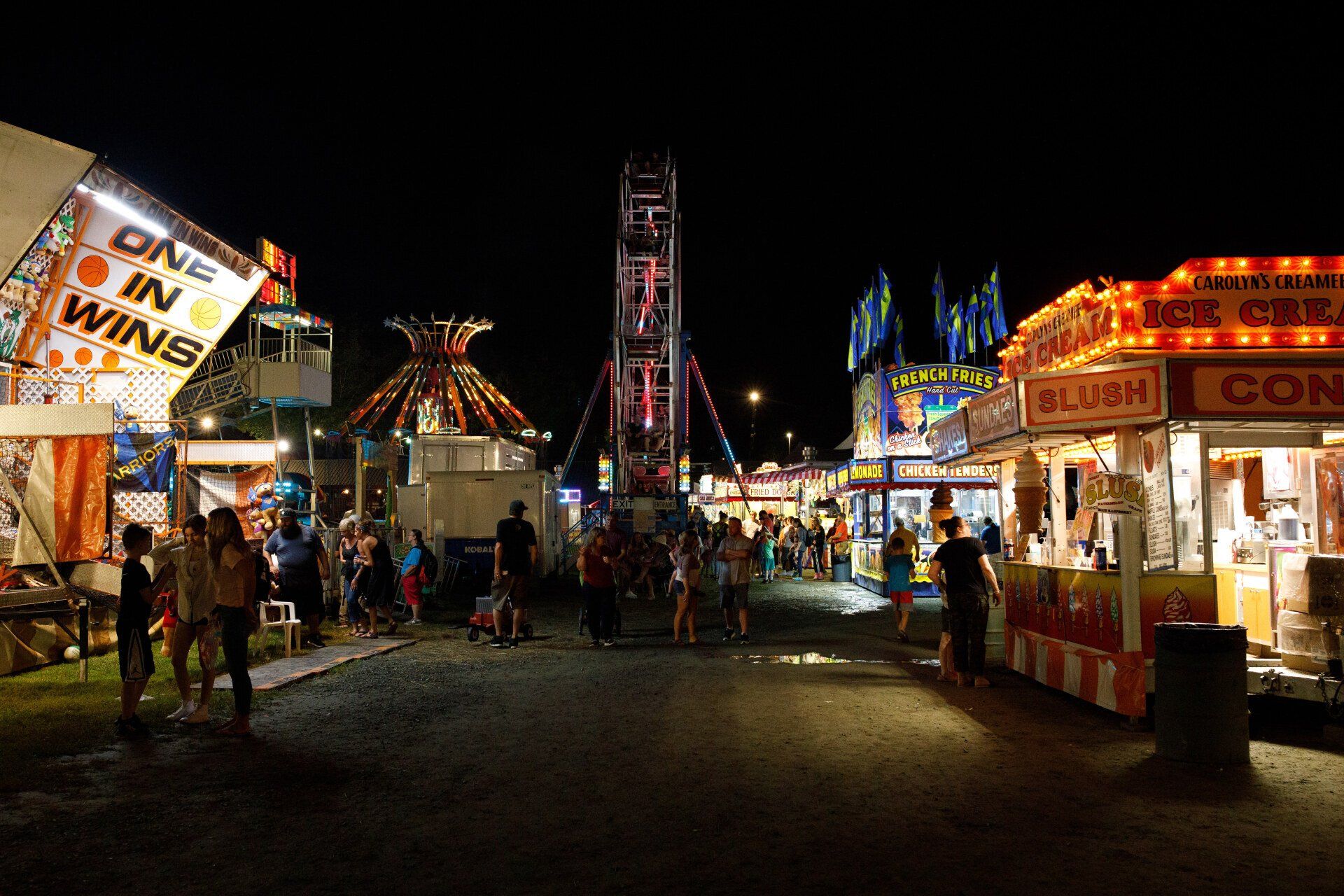 A carnival at night with a sign that says one in wins