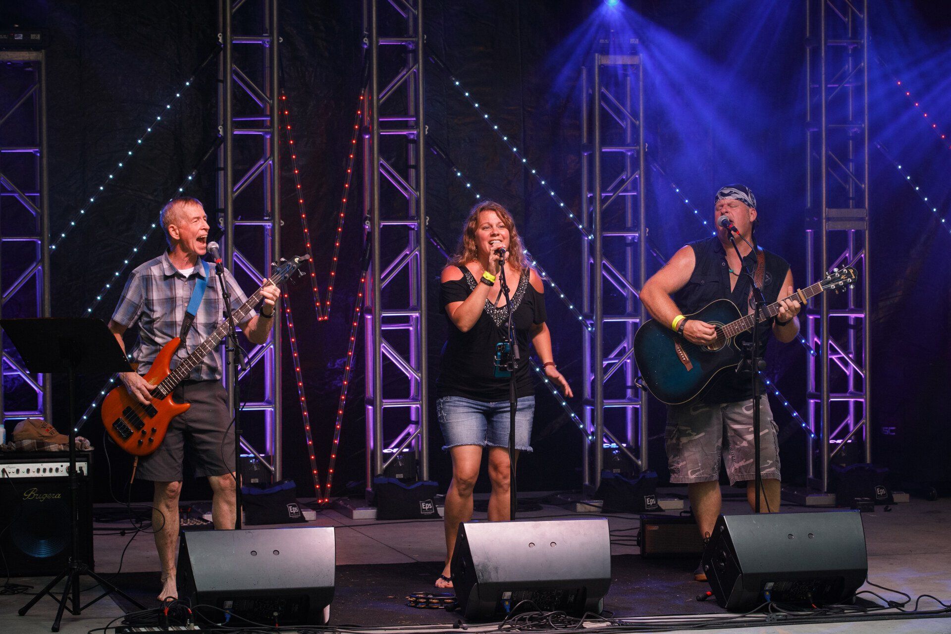 A group of people are standing on a stage playing guitars and singing into microphones.