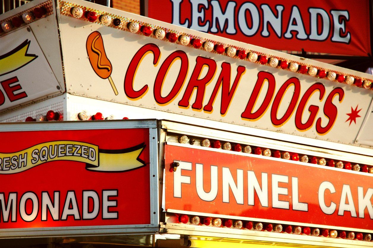 A bunch of food signs including corn dogs and lemonade