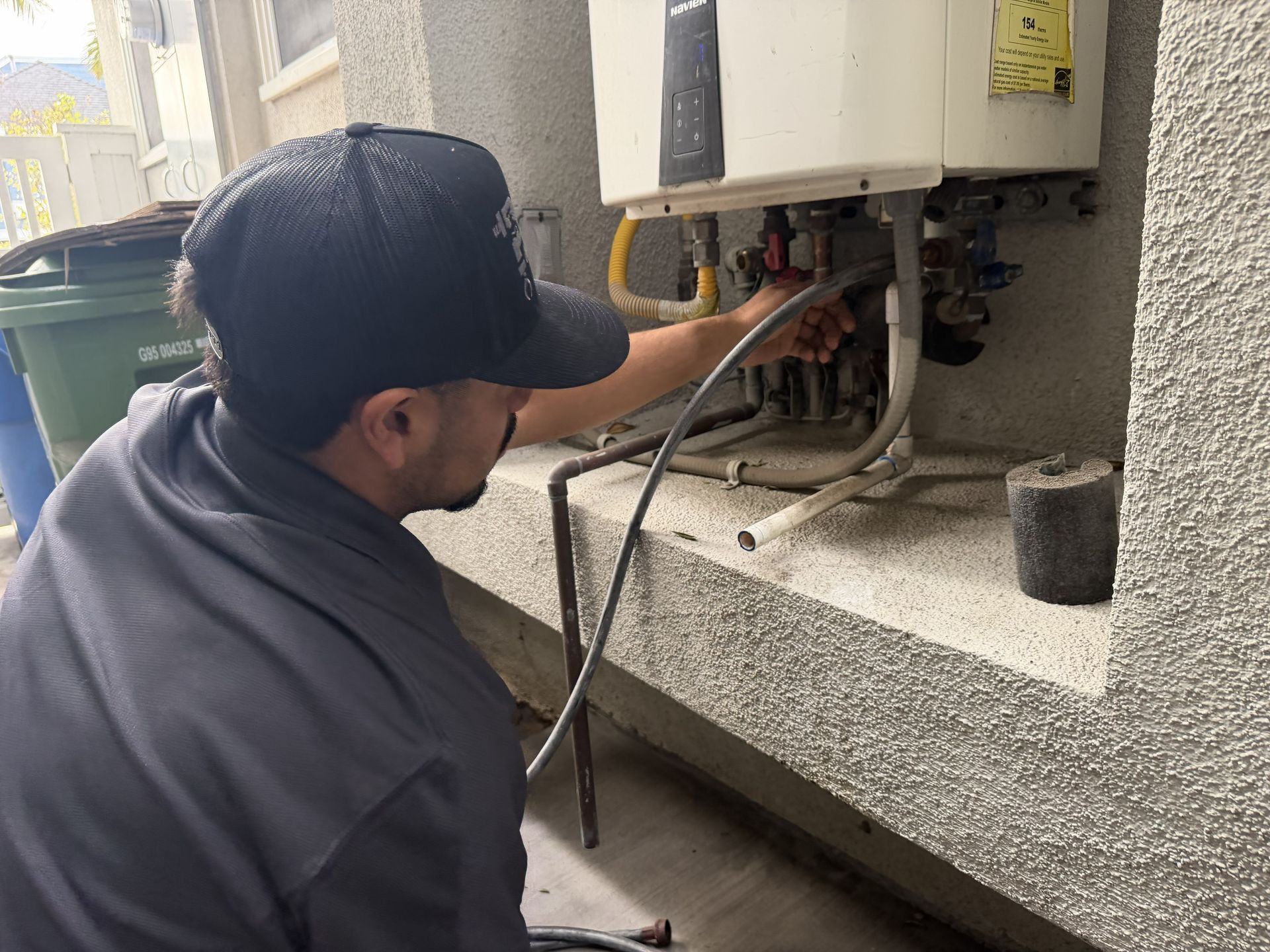 Technician inspecting outdoor electrical unit with cables and open panel