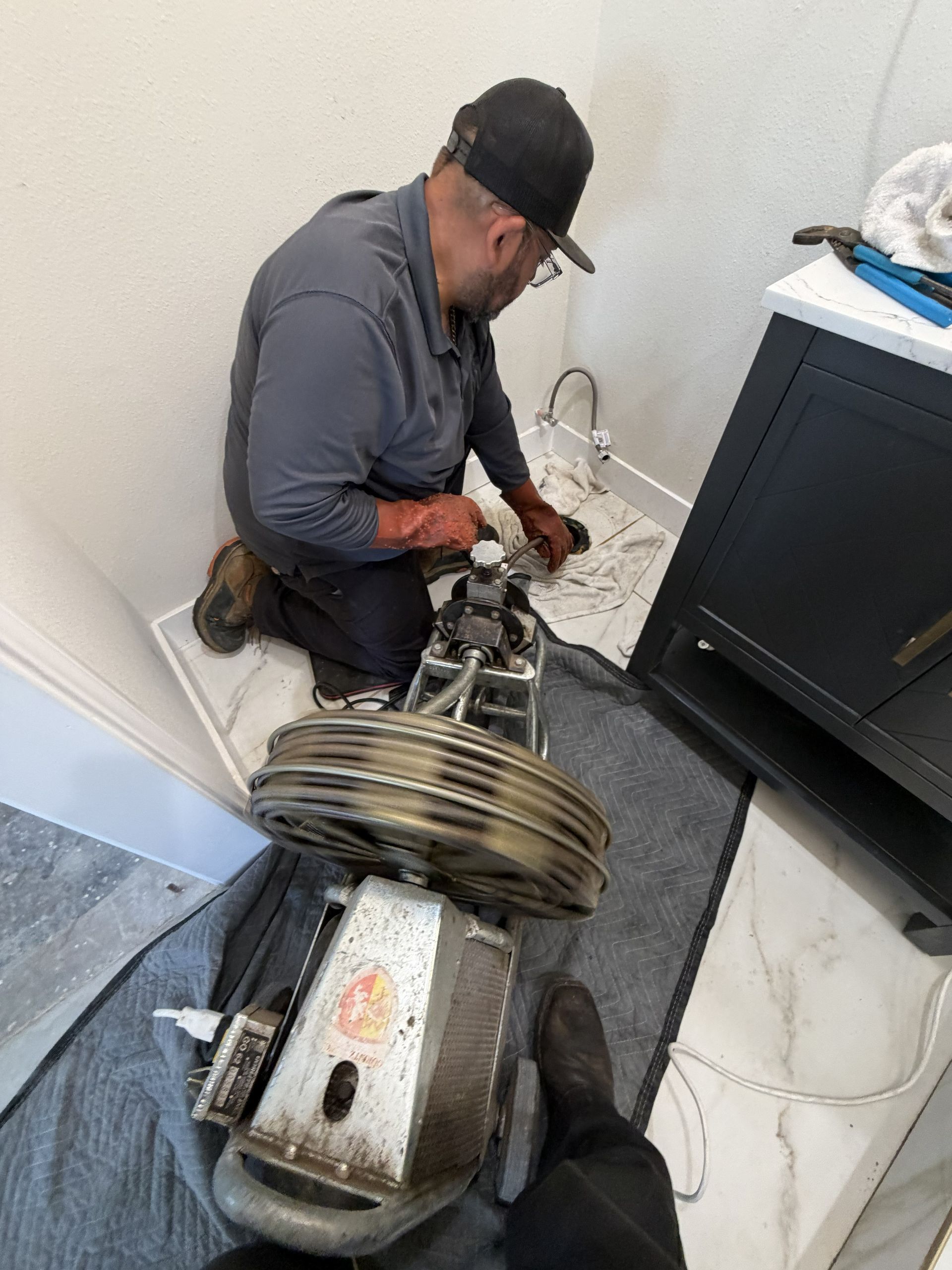Technician repairing a large machine in a utility room, kneeling beside exposed wiring and metal components.