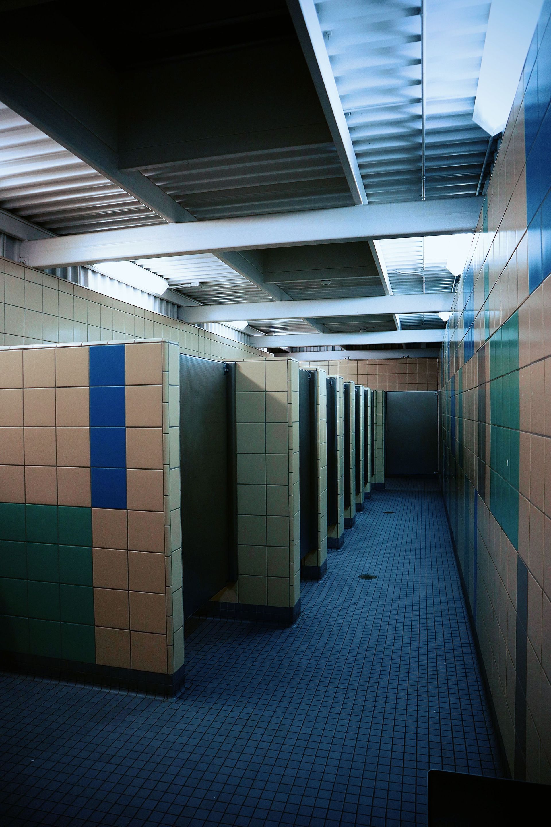 Narrow office corridor with cubicles, blue carpet, and fluorescent ceiling lights