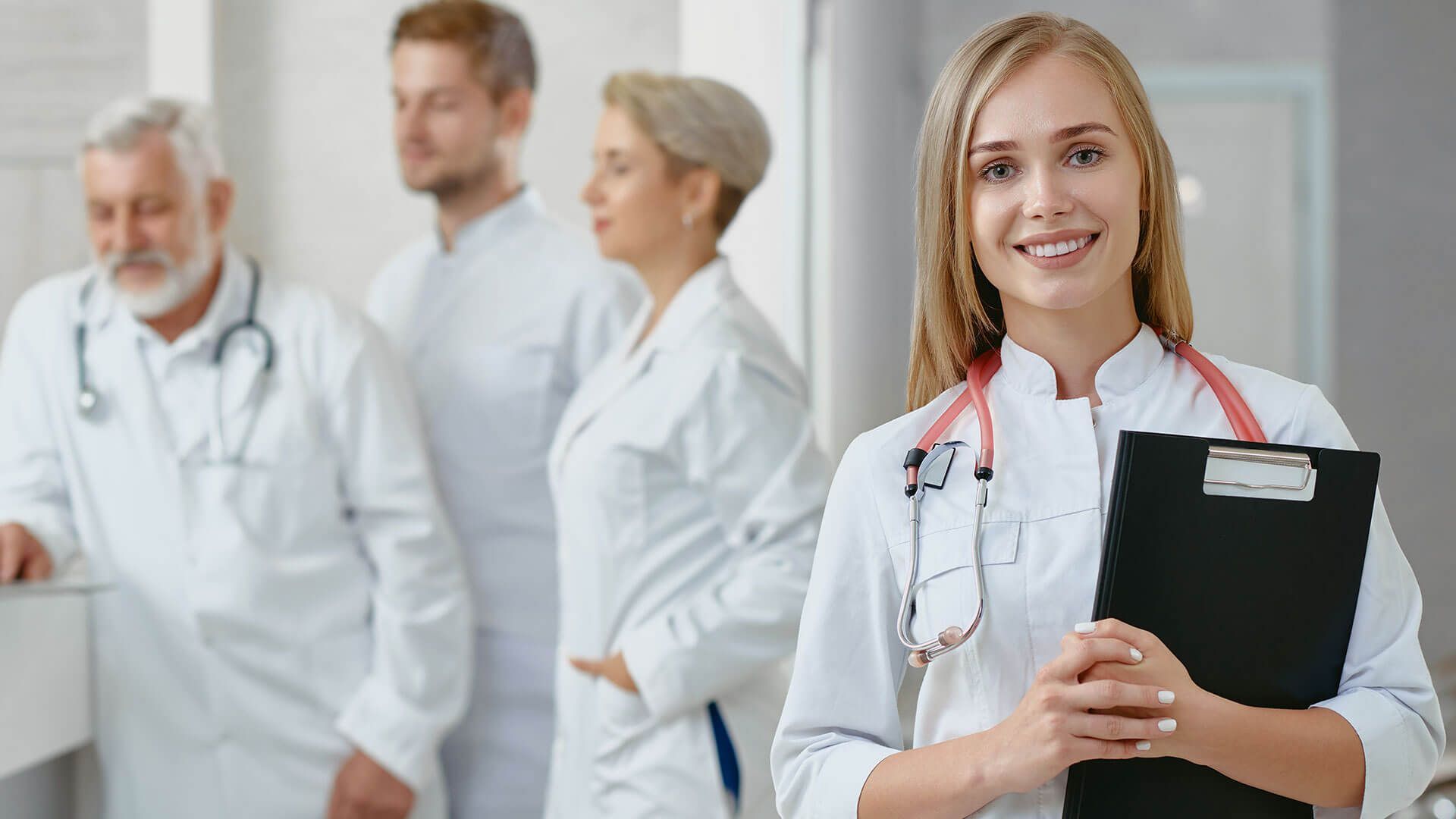 A woman doctor is holding a clipboard in front of a group of doctors.