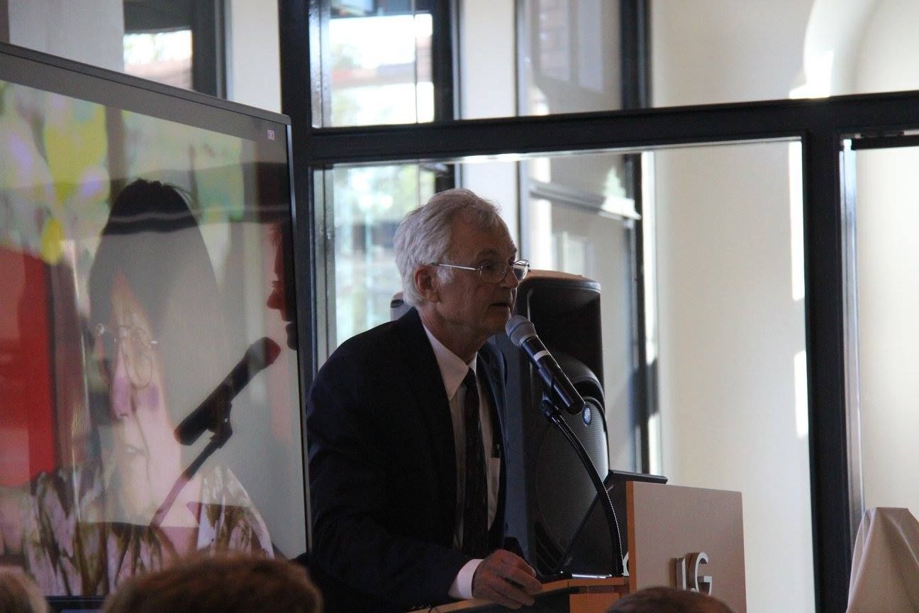 Speaker at a podium addressing an audience in a bright indoor venue