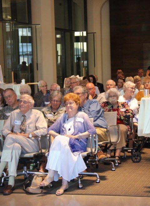 Audience seated in chairs inside a hall, watching an event