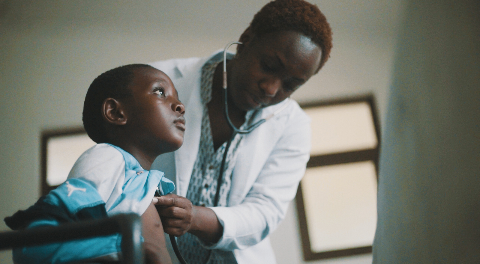 A doctor is examining a young boy with a stethoscope.