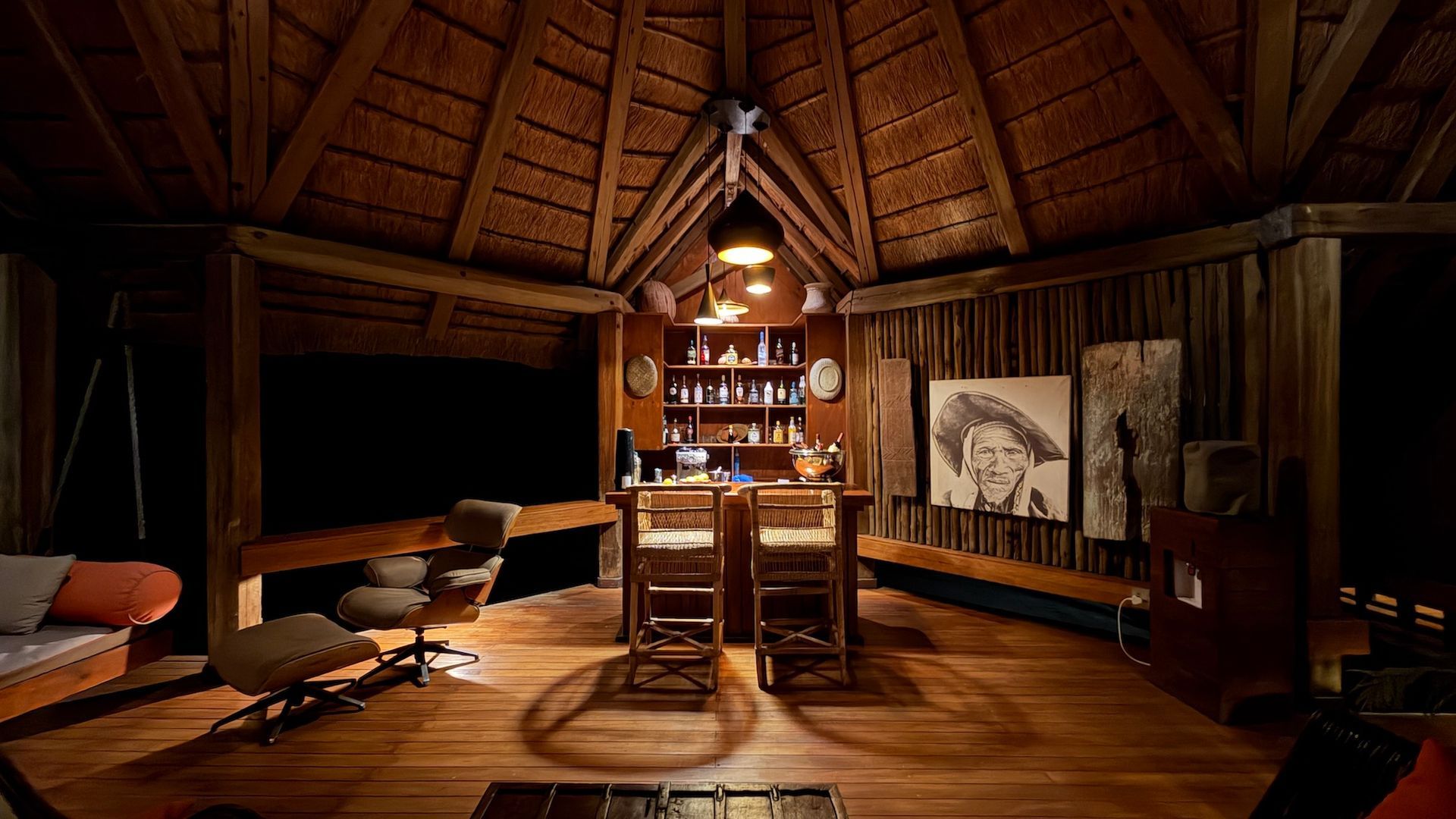 Cozy wooden lodge dining room with a long table, chairs, warm hanging lights, and rustic décor.