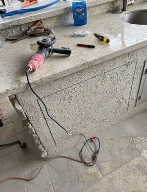 Cordless drill and hand tools on a dusty kitchen counter with cords hanging down