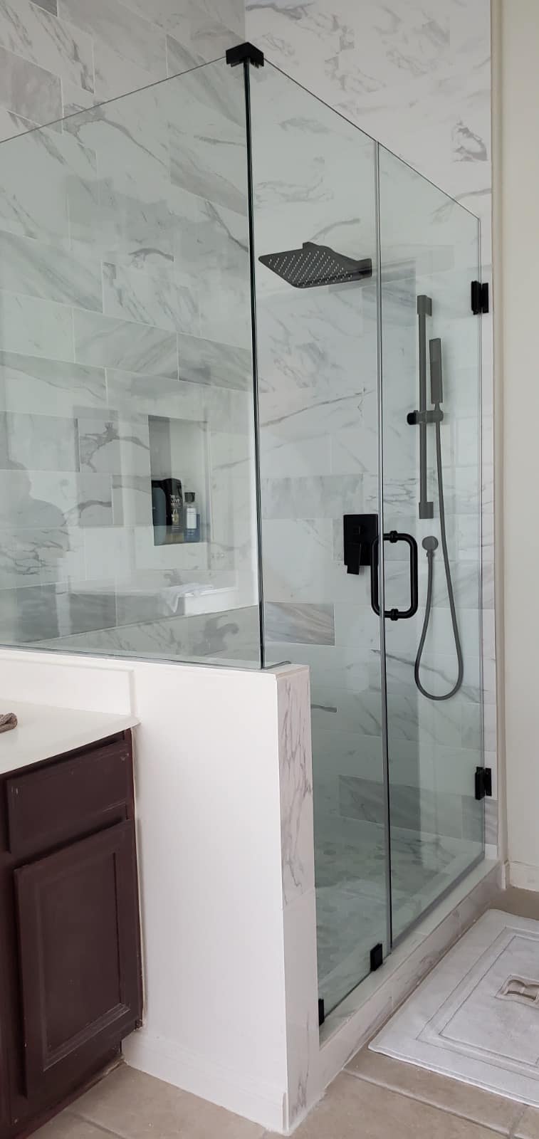Modern bathroom with glass walk-in shower, wall-mounted shower controls, and marble-pattern tile walls