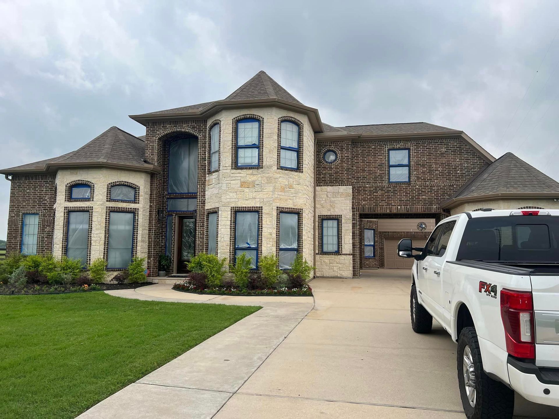 Two-story stone house with a driveway, green lawn, and a white pickup truck parked out front