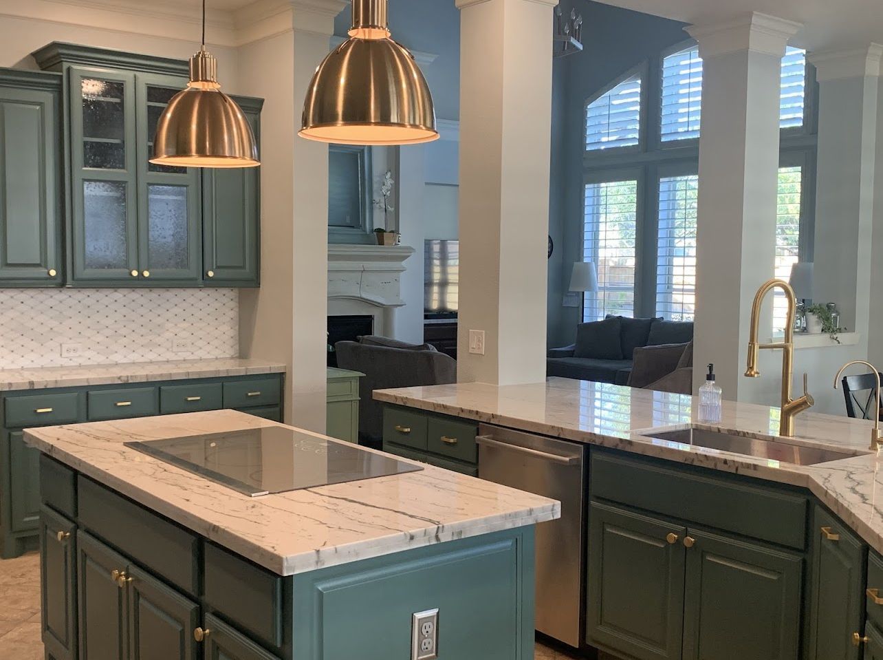 Modern kitchen with teal cabinets, white marble island, and copper pendant lights