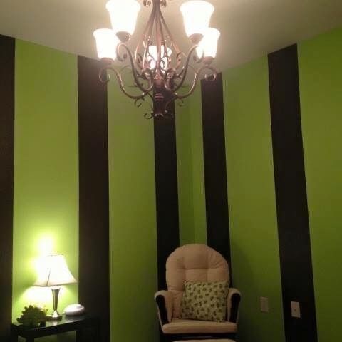 Green-and-black striped room with a chandelier, lamp, and beige armchair with a pillow