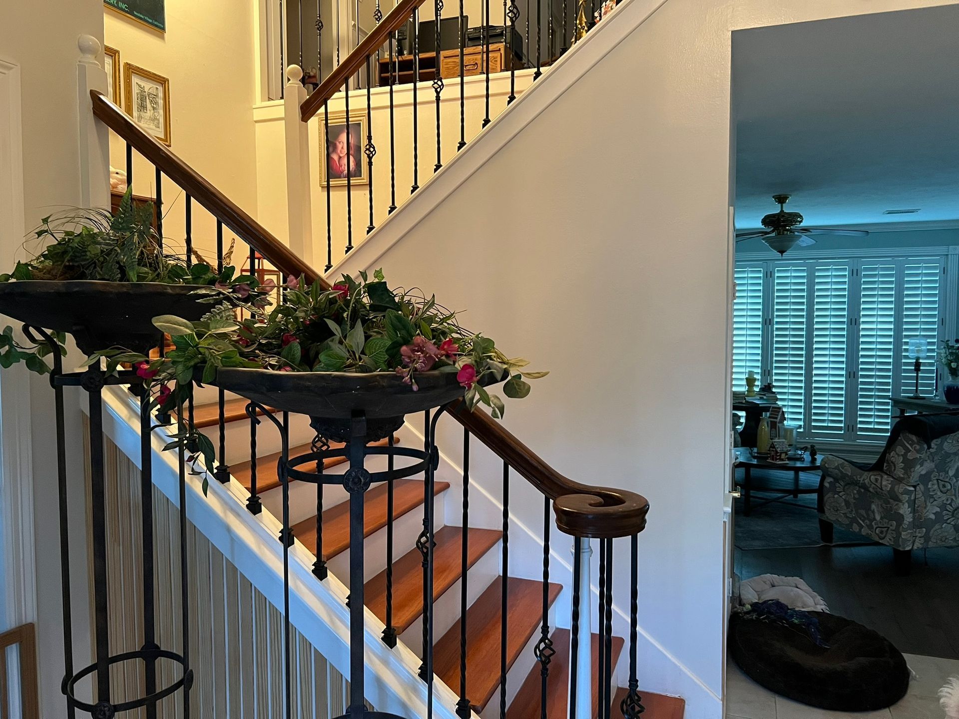 Decorated staircase with garland railing beside a living room with blue-lit windows