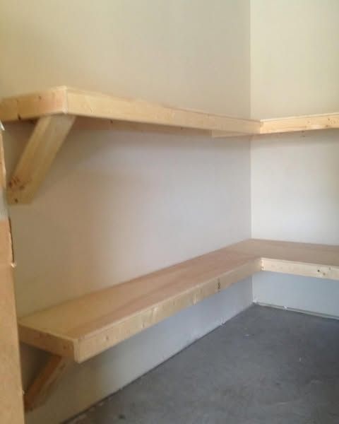 Empty corner with two light wood wall shelves and a gray floor.