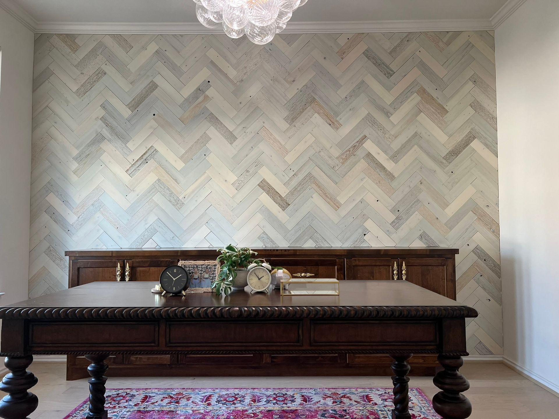 Elegant dining room with a dark wood table, bench, floral centerpiece, and herringbone wallpaper