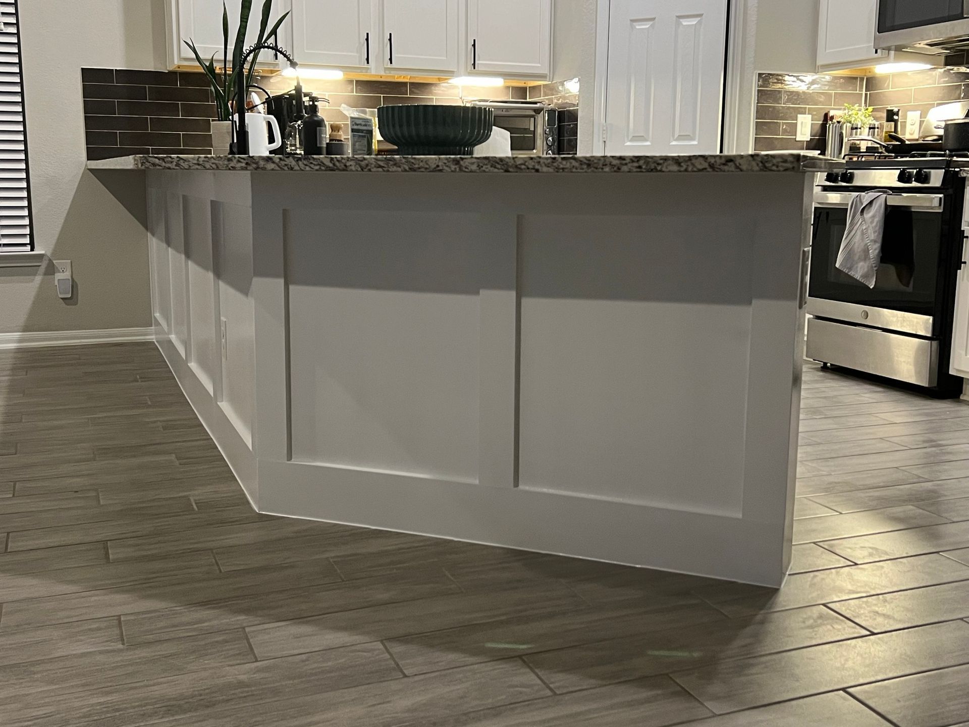 Modern kitchen with gray island, white cabinets, and stainless steel appliances