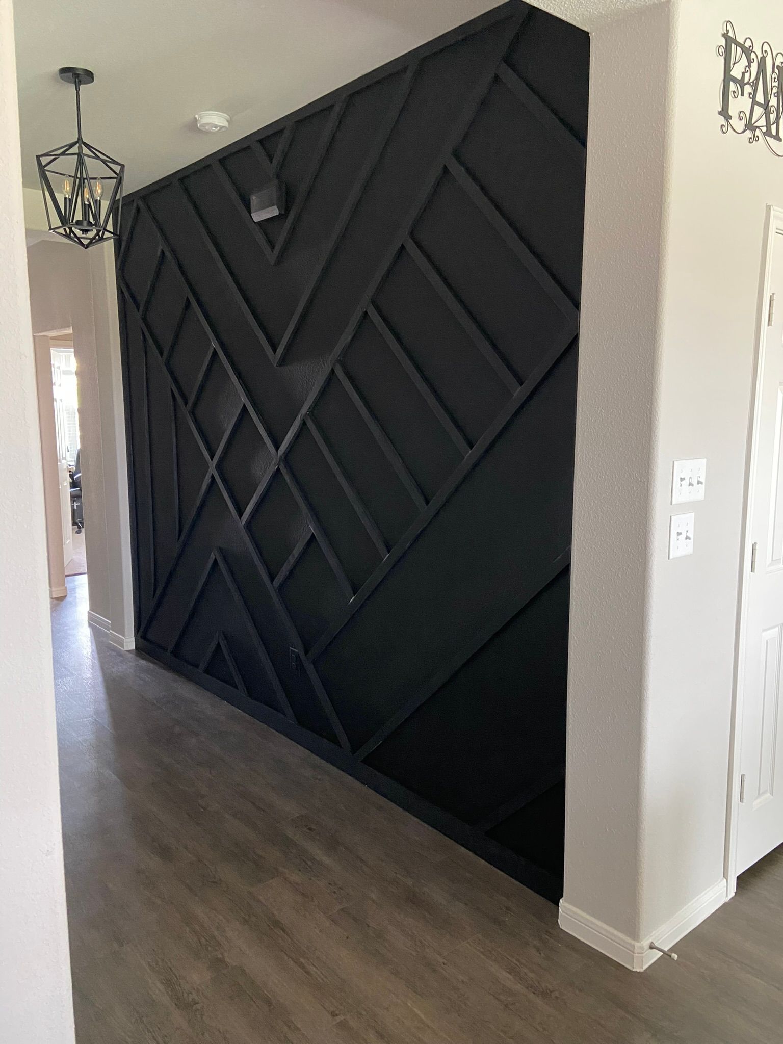Interior hallway with a black geometric accent wall and dark wood flooring