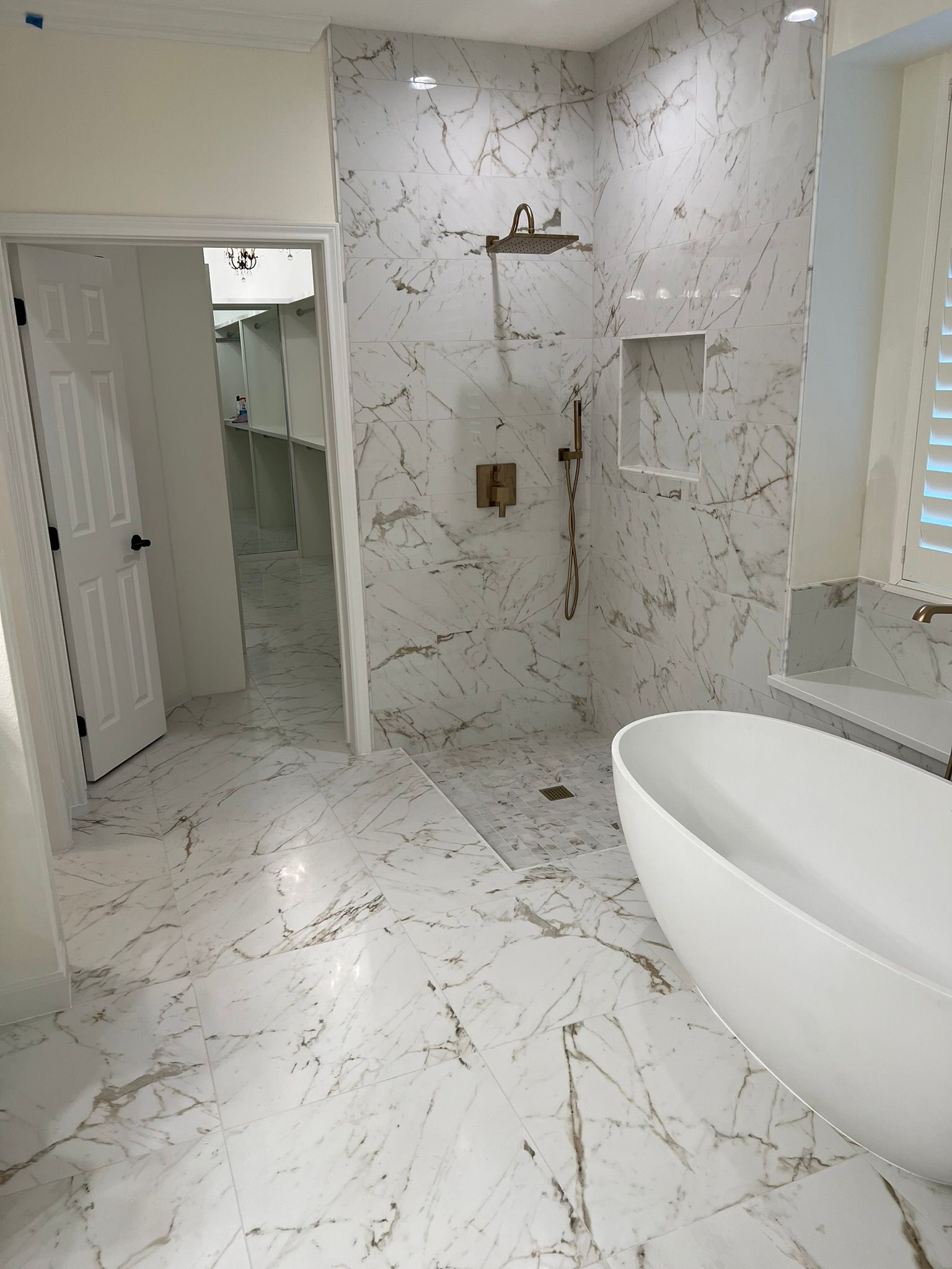 Modern white marble bathroom with walk-in shower, toilet, and freestanding bathtub