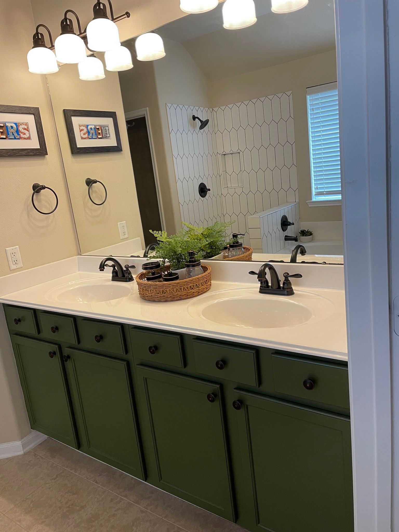 Bathroom vanity with white countertop, green cabinets, double sinks, mirrors, and pendant lights