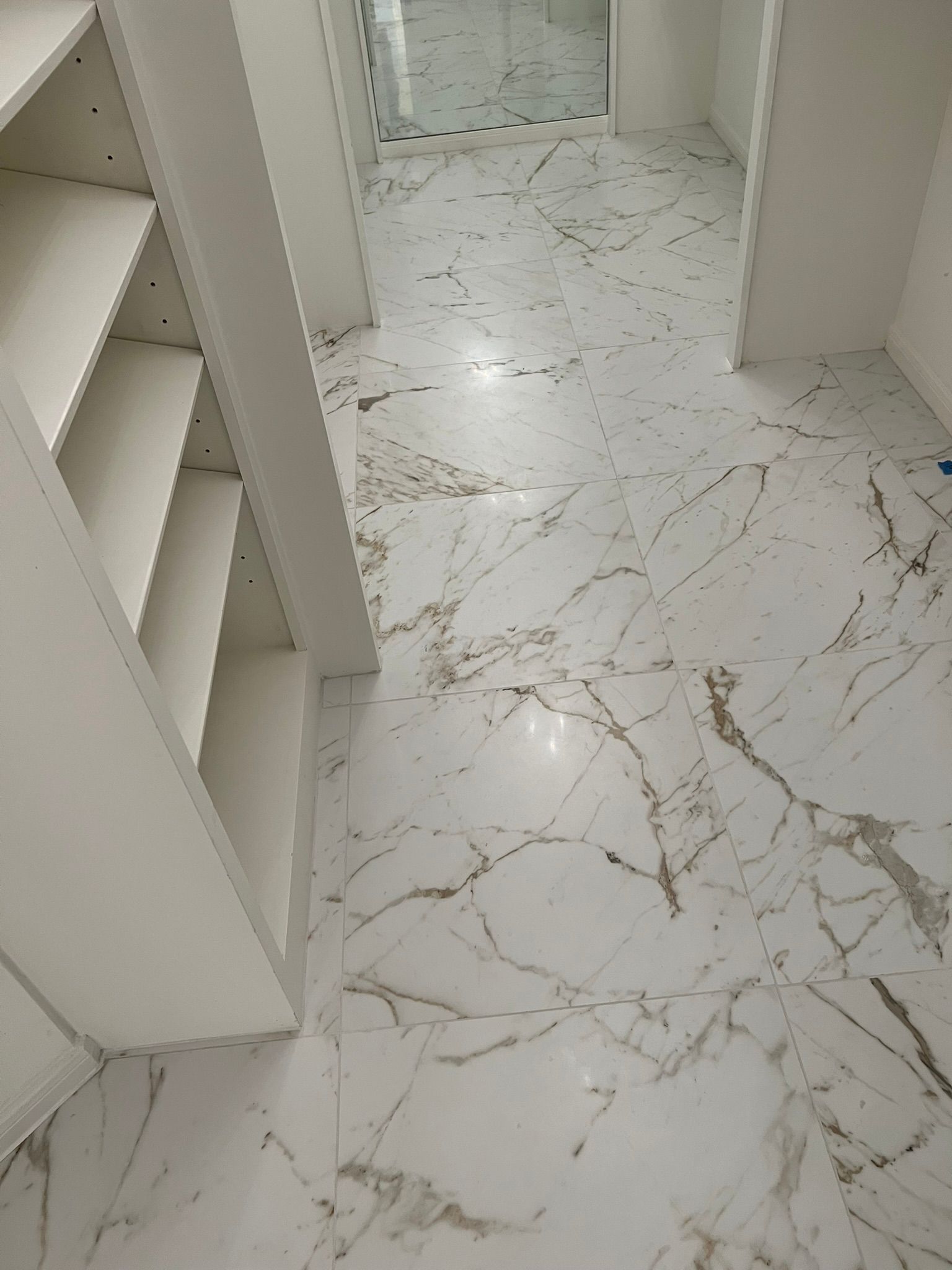 White marble hallway with built-in shelves and doorway, viewed from above