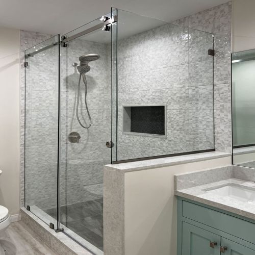 Modern bathroom with glass-enclosed shower, marble tile, built-in niche, and mint vanity sink