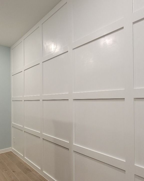 White paneled wall in a room with light wood flooring and gray side walls