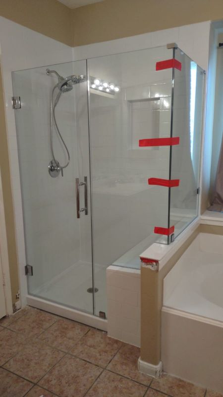 Glass shower enclosure beside a bathtub, with red-striped wall markers and tiled bathroom floor
