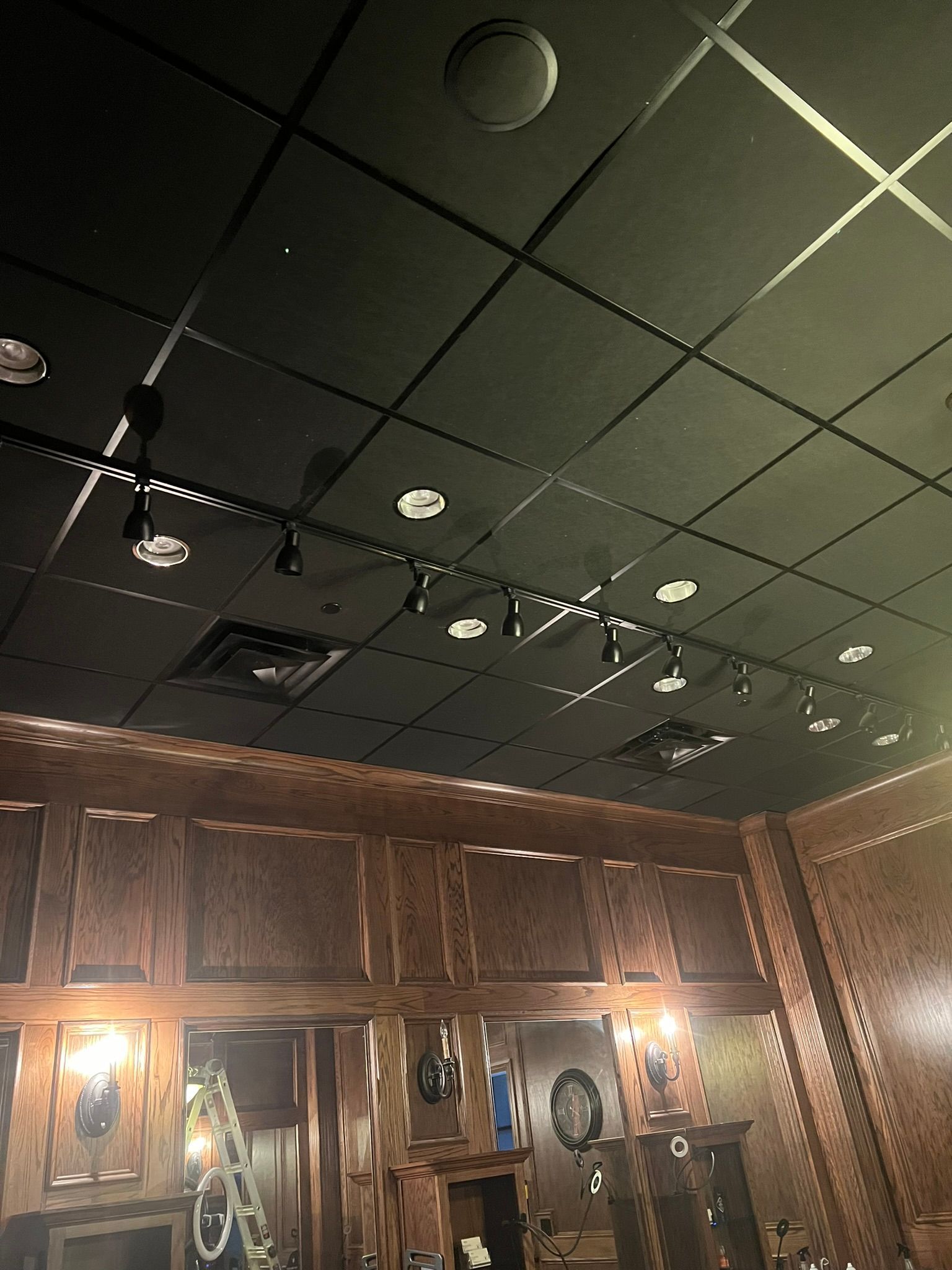 Dim restaurant interior with dark wood walls, ceiling lights, and framed decorations