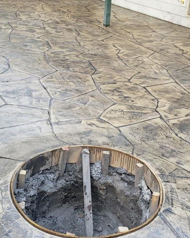 Stamped concrete patio with a large circular hole exposing a damaged underground cavity.