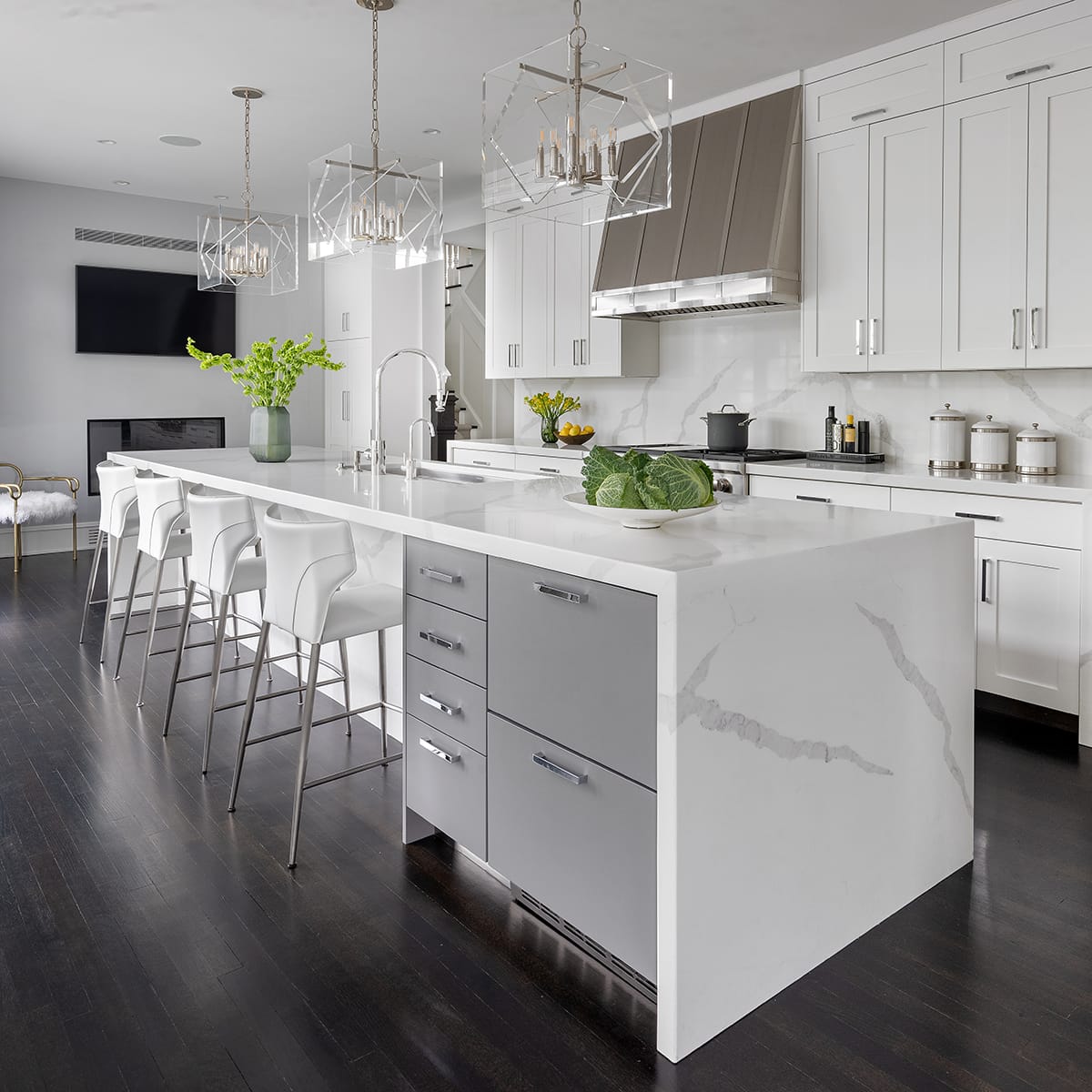 Bright white modern kitchen with marble island, barstools, pendant lights, and dark hardwood floors
