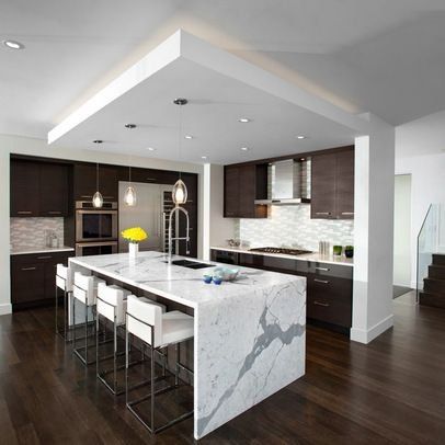 Modern kitchen with dark wood cabinets, white marble island, pendant lights, and stainless steel accents