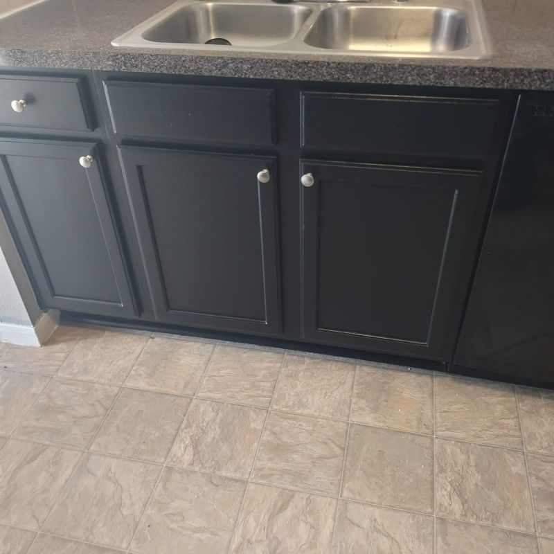 Dark kitchen base cabinets with a double-basin stainless steel sink and tiled floor.