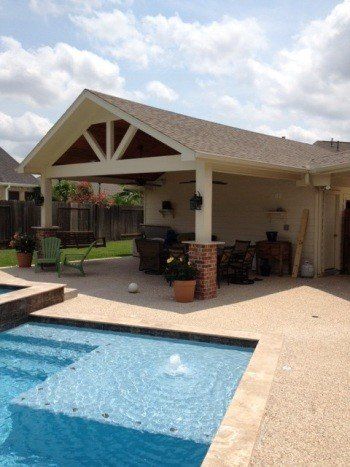 Backyard patio with a swimming pool, covered seating area, and beige house exterior.